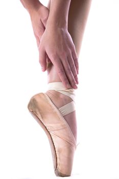 young Caucasian girl in ballet slippers standing on one pointed toe stretching hands to feet