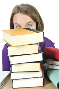 Frustrated teenage girl studying at the desk with big stack of books