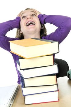 Frustrated teenage girl studying at the desk with big stack of books