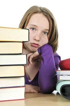 Frustrated teenage girl studying at the desk with big stack of books