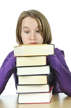 Frustrated teenage girl studying at the desk with big stack of books