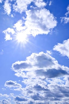 Background of blue sky with shining sun and clouds