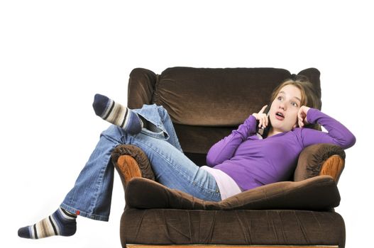 Teenage girl talking on a phone sitting in an armchair