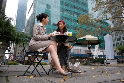 Two business women having a casual meeting or discussion in the city. 