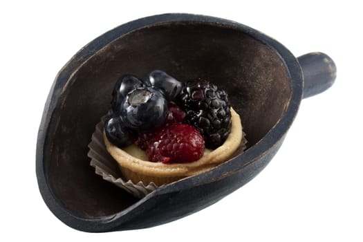 mini fruit tart with blueberries, blackberry and raspberry on a rustic, wooden scoop isolated on white