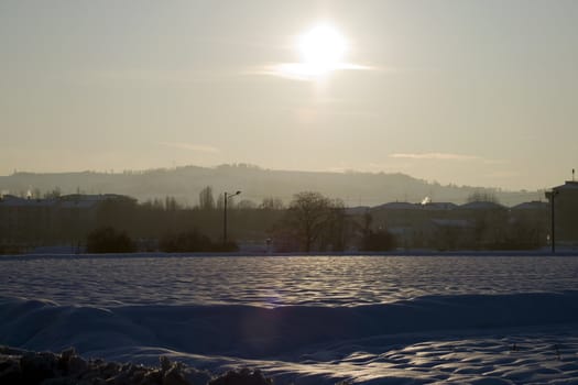 Landscape of country under the snow, with great sun in front