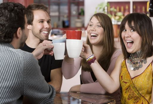 Young toasting friends with coffee cups in a cafe