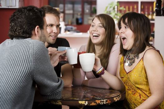 Young toasting friends with coffee cups in a cafe