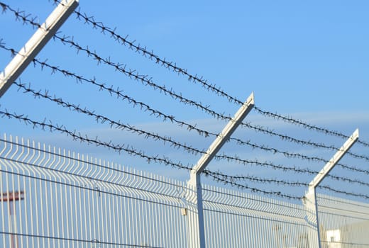 Barbed wire fence on background with blue sky