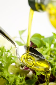 Pouring olive oil in the salad over a spoon
