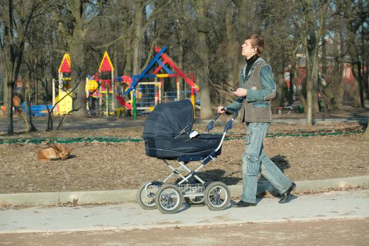 young father with sidercar on walk in spring park listens music, editorial use only