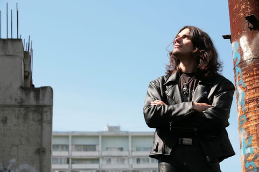 man in black leather cloth in gothic style near rusty metallic pipe with copy-space