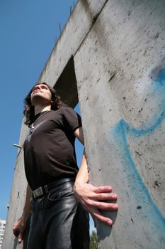 man in black leather cloth amongst iron-concrete construction