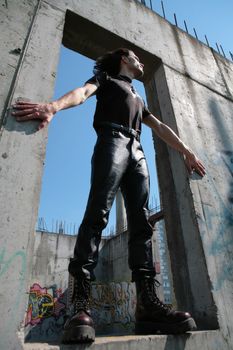 man in black leather cloth amongst iron-concrete construction