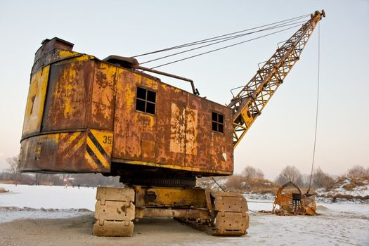 rusty old yellow excavator on a winter day