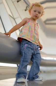 One blondie girl standing next a large metal tube at industrial set. Looking at the camera from bottom view.