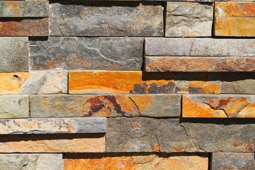 Sun lit tightly fitting rectangular red and gray stone wall 