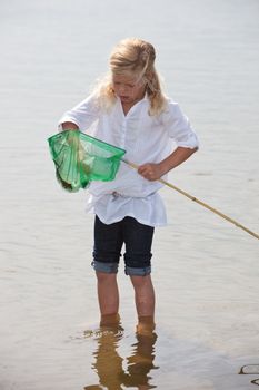 Little girl with a net to catch shrimps from the sea