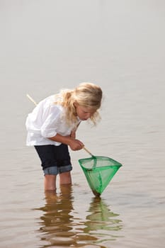 Young kid checking the content of her net to see if she has caught anything