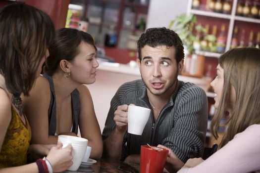 Handsome young man in a coffee house surrounded by pretty women