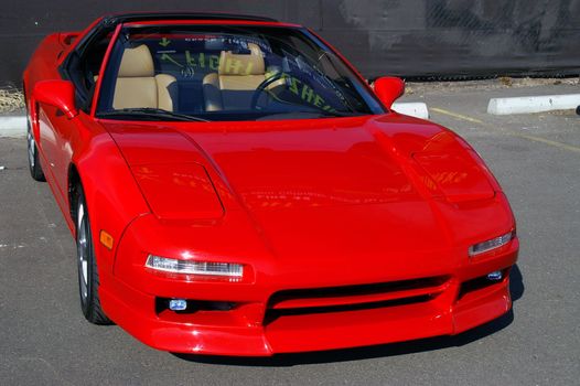 Red Acura NSX sits idle in the sunlight

