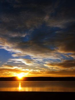 Sunrise and clouds on a lake beach with blue sky