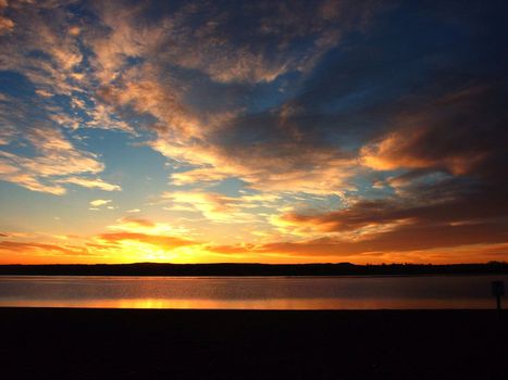 Sunrise on a beach with clouds against blue sky