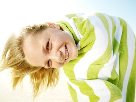 Caucasian girl with towel wrapped around her looking at viewer.