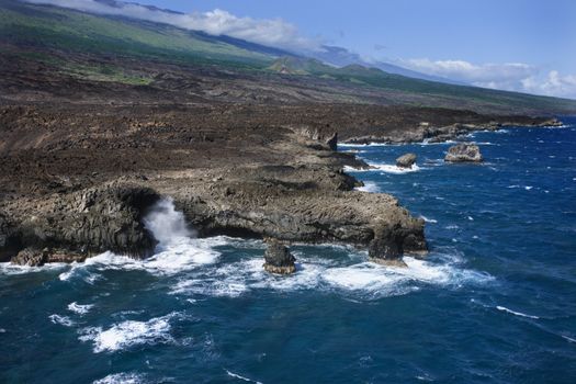 Aerial of Pacific ocean and Maui, Hawaii coast with waves hitting lava rocks.