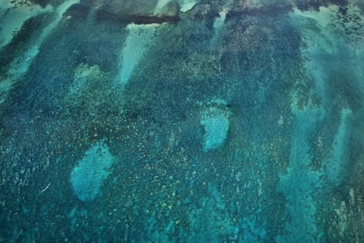 Aerial of reef seen through blue Pacific ocean.