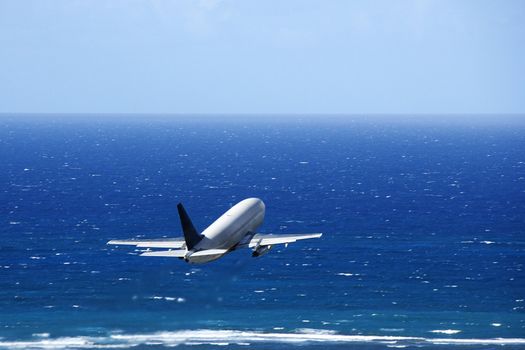 Passenger airplane taking off from airport headed over the Pacific ocean.