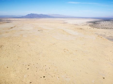 Aerial view of remote California desert with mountain range in background.