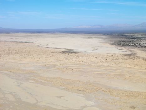 Aerial view of remote California desert with mountain range in background.