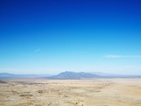 Aerial view of remote California desert with mountain range in background.