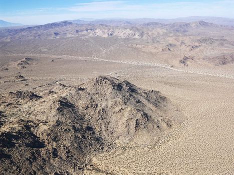 Aerial view of remote California desert with mountain range in background.