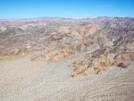 Aerial veiw of remote California desert with mountain range in background.