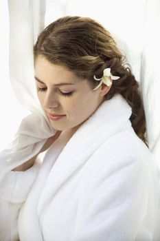 Pretty Caucasian mid-adult woman wearing white terry robe with white orchid flower in hair.