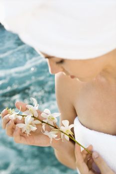 Pretty Caucasian mid-adult woman wearing towel on head holding flowers beside pool.