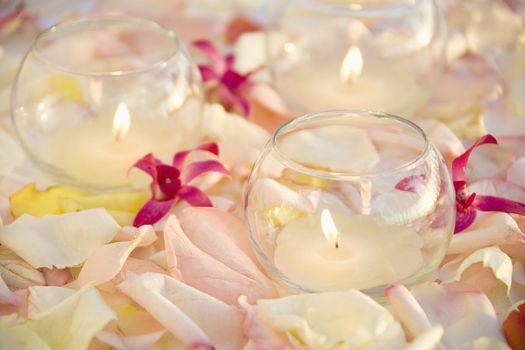 Lit candles with purple orchids and rose petals.