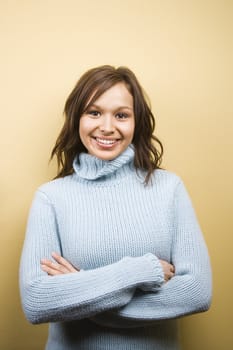 Young adult Caucasian woman wearing sweater with arms crossed and smiling at viewer.