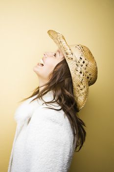 Profile of young adult Caucasian woman wearing cowboy hat leaning backwards laughing.