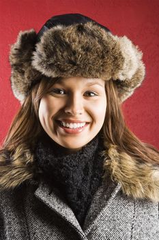 Young adult Caucasian woman wearing fur hat smiling at viewer.