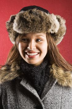 Young adult Caucasian woman wearing fur hat looking to side and smiling.