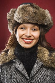 Young adult Caucasian woman wearing fur hat smiling at viewer.