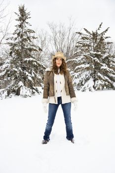 Caucasian young adult female standing in snow wearing straw cowboy hat.