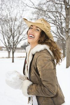 Caucasian young adult female smiling at viewer while holding snowball and wearing straw cowboy hat.