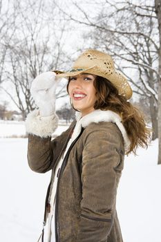 Caucasian young adult female smiling and tilting straw cowboy hat at viewer.