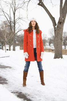 Caucasian young adult female looking at viewer and standing in snow covered street.