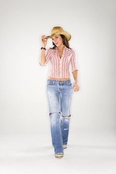 Young Caucasian woman walking to viewer and tilting cowboy hat.