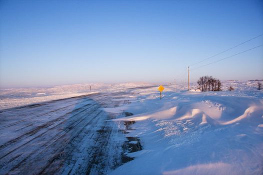 Ice covered road and snowy rural landscape.